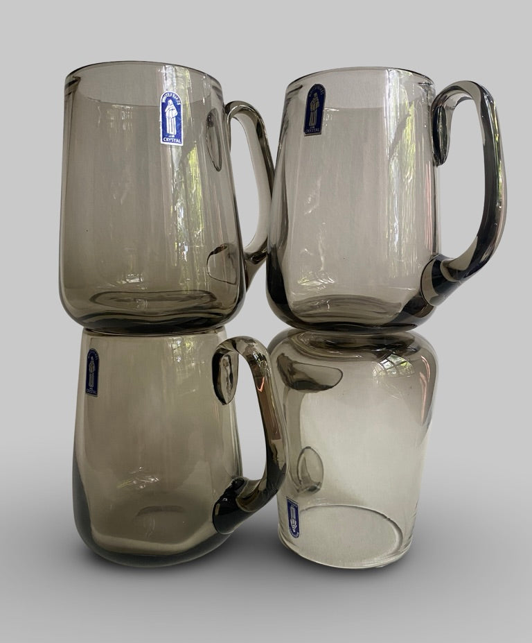 Four smoked glass mugs stacked on a light gray background